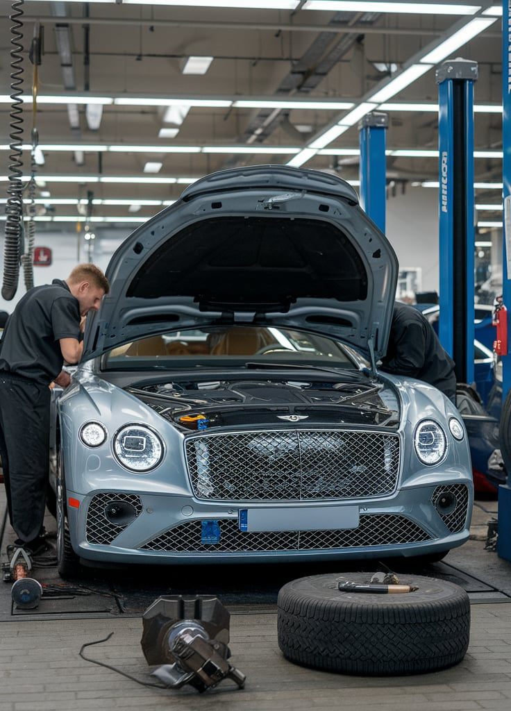 Mechanics inspecting Bentley in service center.